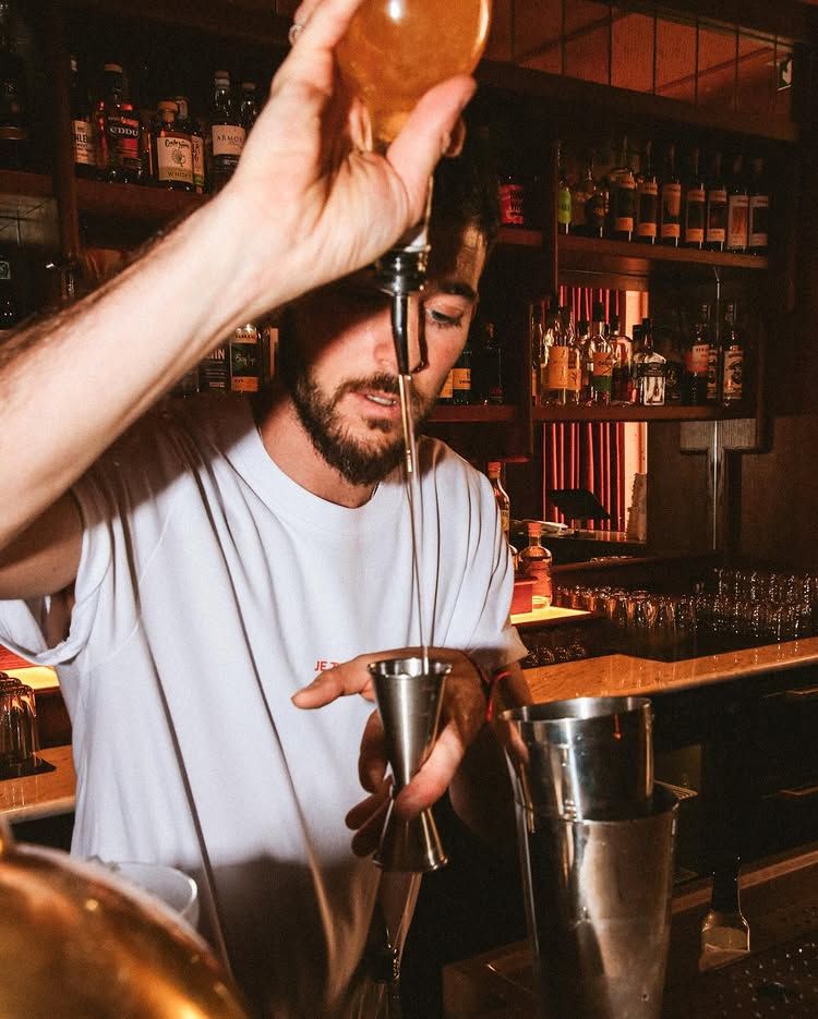 Bartender free-pouring a cocktail behind the bar