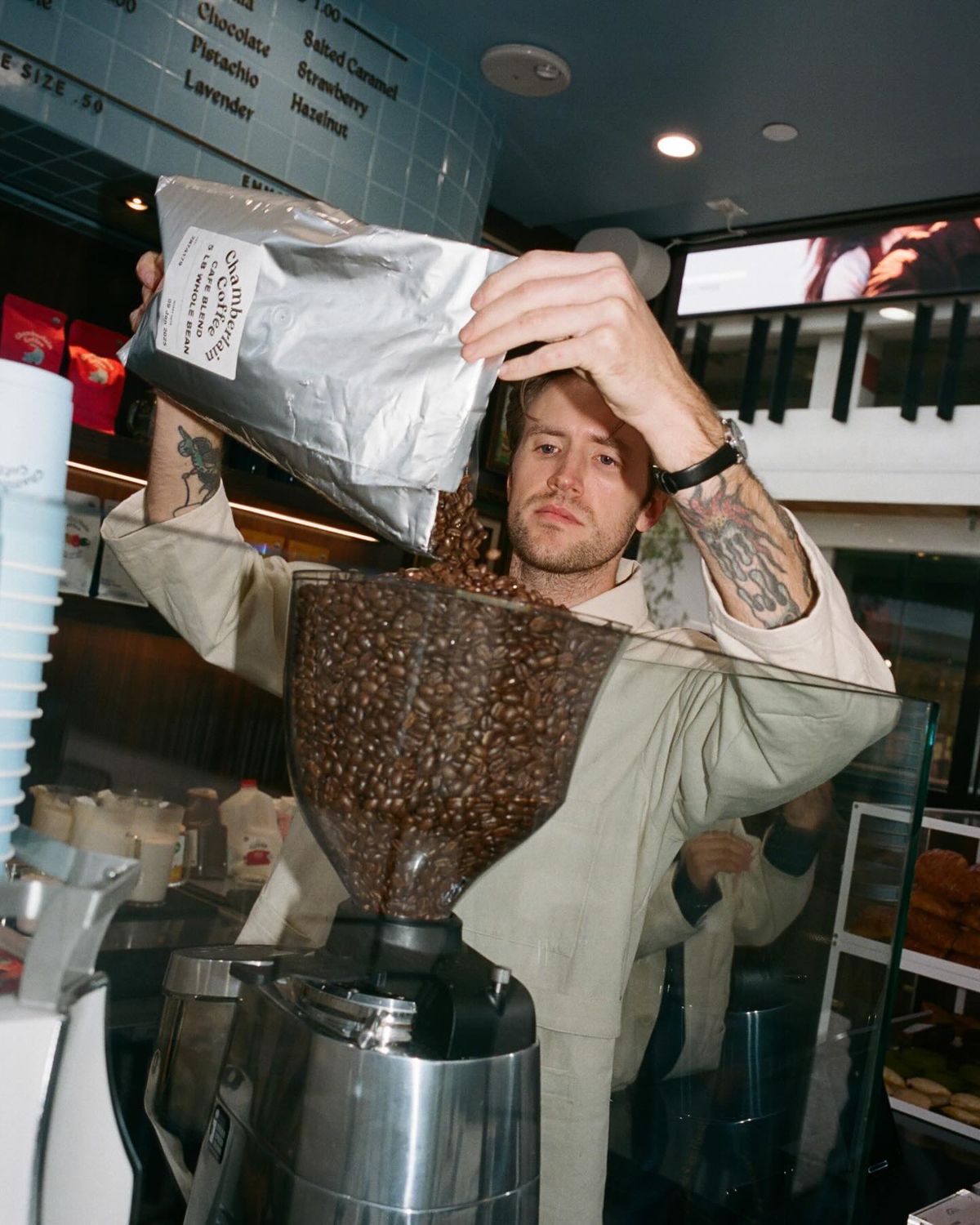 Barista pouring a bag of coffee beans into a grinder