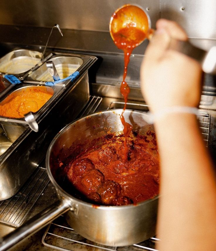 Ladle pouring sauce into a steel pot